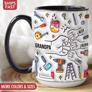 Peut inclure: Mug en céramique blanche avec une anse et un bord noirs, orné d'un motif d'outils, de mains et du mot "GRANDPA". Les noms "ALEX", "OLIVIA" et "CHRIS" sont également inclus. Le mug est posé sur une surface en bois.