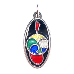 May include: Oval pendant with a silver-tone frame and a colorful abstract design. The design features red, yellow, green, and blue shapes on a black background, with a small, round, clear stone. The pendant has a small loop at the top for a chain.