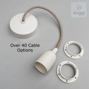 May include: White pendant light fitting with a beige and white braided cable, a white ceiling rose, and two white mounting rings. The text "Over 40 Cable Options" is visible. The logo "duggi" is in the upper right corner.