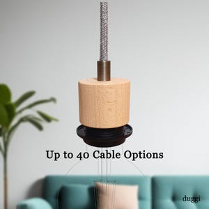 May include: A pendant light fitting with a cylindrical wooden shade and a braided grey cable. The fitting has a black base and a metal accent. Text on the image reads "Up to 40 Cable Options."