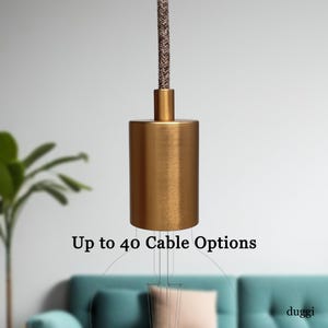 May include: A gold-coloured cylindrical pendant light fitting with a brown and white braided cord. The text "Up to 40 Cable Options" is displayed below the fitting.