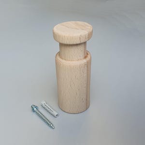 May include: A natural wood wall mount with a round top and a cylindrical base. It comes with a screw and a plastic anchor for installation.
