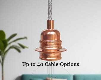 Op de afbeelding: Een koperkleurige hanglamp met een grijs met stof bekleed snoer. De armatuur heeft een lamphouder en een ronde basis. De tekst op de afbeelding luidt "Up to 40 Cable Options."