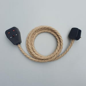 Op de afbeelding: Een zwarte stekker en stopcontact met een beige gevlochten snoer. Het snoer is opgerold in een cirkelvorm. De stekker en het stopcontact zijn zwart met rode en witte accenten. De kabel is ongeveer 100 cm lang.