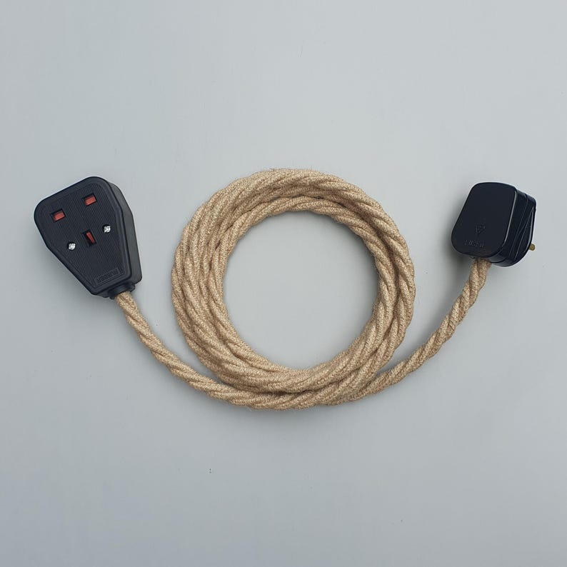 Op de afbeelding: Een zwarte stekker en stopcontact met een beige gevlochten snoer. Het snoer is opgerold in een cirkelvorm. De stekker en het stopcontact zijn zwart met rode en witte accenten. De kabel is ongeveer 100 cm lang.