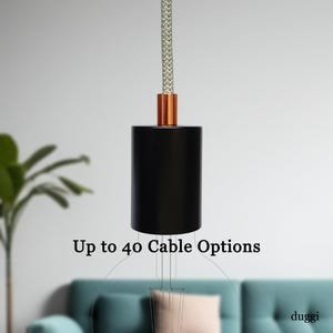 May include: A black cylindrical pendant light fitting with a copper-coloured accent and a grey and white braided cord. The text "Up to 40 Cable Options" is displayed below the fitting.