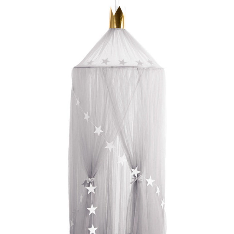 Pode incluir: Um dossel de tule cinza com uma coroa dourada no topo. O dossel tem estrelas brancas costuradas.