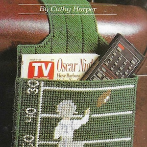 May include: A green crocheted armchair organizer with a football player design and the words "Armchair Quarterback" and "By Cathy Harper". The organizer has a pocket for a TV guide and a remote control.