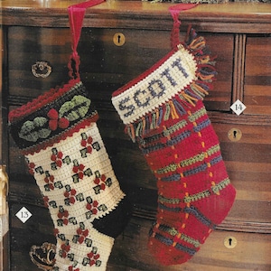 Puede incluir: Dos calcetines de Navidad de ganchillo colgados de una cómoda de madera. Un calcetín es blanco con detalles rojos y verdes y el otro es rojo con detalles verdes, azules y naranjas. El calcetín rojo tiene el nombre "Scott" tejido en la parte delantera.
