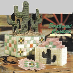 May include: A set of four crocheted coasters with a cactus design, and a matching holder for the coasters. The coasters are in shades of pink, green, and white. The holder is in shades of yellow, green, and white. The coasters are labeled "Southwest Coasters" and "By Michele Wilcox".