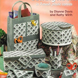 Pode incluir: Um padrão de ponto de cruz em tela plástica para um projeto com tema de sala de costura. O padrão inclui instruções para fazer uma bolsa, uma caixa, um almofada para alfinetes, um porta-lápis e um porta-tesoura. O padrão é verde e branco com um design geométrico.