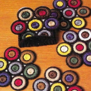 May include: Set of six colorful crocheted coasters with a circular pattern. Each coaster features a central circle surrounded by smaller circles in various colors, including red, yellow, blue, green, and brown.
