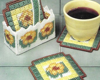 Puede incluir: Conjunto de cuatro posavasos florales amarillos y verdes con un soporte a juego. Los posavasos están hechos de lona de plástico y presentan un diseño floral sencillo. El soporte es un contenedor tipo cesta con asa.