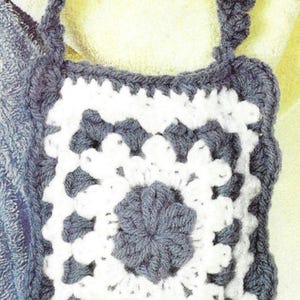 May include: A crocheted bag with a white and grey square design. The bag has a single strap.