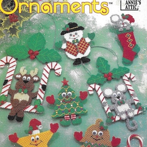 Puede incluir: Un conjunto de nueve adornos de lona de plástico con un muñeco de nieve, un reno, un árbol de Navidad, un hombre de jengibre, una estrella y dos ratones. Los adornos están decorados con bastones de caramelo y acebo. El título "Fast & Fun Ornaments" está impreso en la parte superior de la imagen. La imagen es de Annie's Attic.