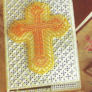 May include: A white crocheted book cover with a yellow and orange cross design.