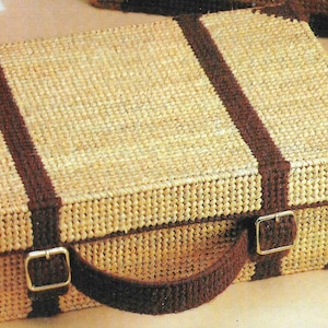 May include: A brown and tan woven suitcase with a brown handle and two buckles. The suitcase has brown stripes on the top and sides.