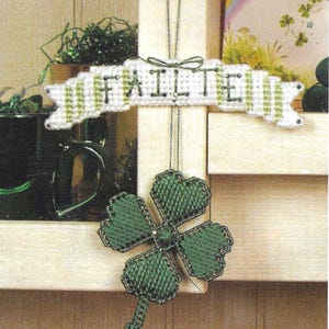 May include: A white banner with green stripes and the word "Failte" hanging from a knob. A green four-leaf clover with a chain-like stem hangs below the banner.