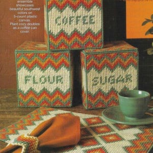 May include: A set of three square storage containers with the words "COFFEE", "FLOUR", and "SUGAR" stitched on them. The containers have a southwestern design in orange, green, and white. A matching placemat, napkin, and cup are also visible.