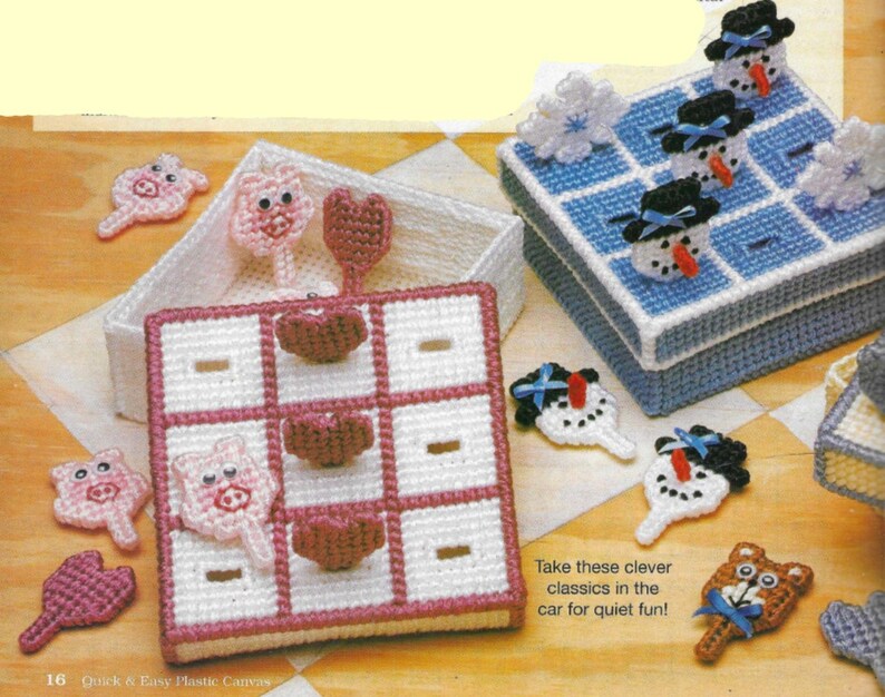 May include: Two plastic canvas game sets, one with a pink and white tic-tac-toe board and pink pig pieces, the other with a blue and white tic-tac-toe board and white snowman pieces.  The text "Take these clever classics in the car for quiet fun!" is printed below the game sets.