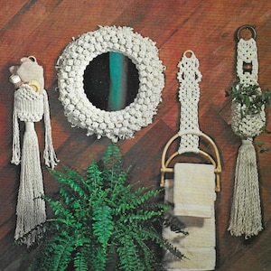 以下が含まれることがあります： バスルームに飾られたマクラメの壁掛けセット。セットには、丸い鏡、タオルラック、プラントハンガーが含まれています。マクラメのすべての作品は白いコードで作られており、フリンジのディテールがあります。