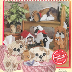 May include: A collection of plastic canvas patterns featuring various dog designs. The patterns include a dog house, a beagle lying down, a dog with a bone, a dog with a puppy, and two tissue box covers with dog faces. The text "Winning Plastic Canvas! Patterns" is displayed on a red and white starburst.