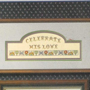 May include: A framed cross-stitch design with a white background and a green, brown, and yellow arched banner that reads "Celebrate His Love".