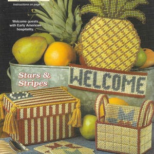 May include: A collection of handmade needlepoint crafts, including a pineapple-shaped welcome sign, a box with a flag design, and a basket. The crafts are in shades of yellow, red, and blue, with the word "WELCOME" prominently displayed. The image also includes fruit.