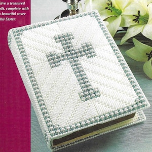 May include: White canvas book cover with a blue cross design. The cover has a blue and white border.