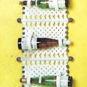 May include: White macrame wall hanging with beaded fringe and five empty wine bottle holders.