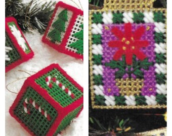 May include: Four handmade Christmas ornaments made with plastic canvas. The ornaments are shaped like cubes and feature different holiday designs. One ornament has a green and white candy cane design, another has a green Christmas tree, and the last one has a red poinsettia.