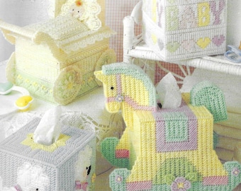 Pode incluir: Cinco capas diferentes para caixas de lenços de papel em um tema de berçário. As capas são feitas de tela de plástico e apresentam um carrinho de bebê, um cavalinho de balanço, um cordeiro, um urso de pelúcia e um bloco com a palavra "bebê" nele.