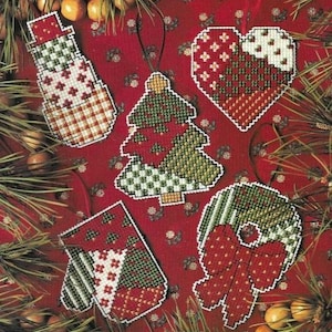 May include: Five Christmas ornaments with a patchwork design. The ornaments are a snowman, a Christmas tree, a heart, a wreath, and a mitten. The ornaments are all made of fabric and have a variety of colors and patterns.