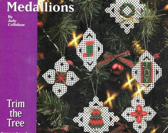 May include: A book titled "Yuletide Medallions" by Judy Collishawwith the subtitle "Trim the Tree: Treasured touches for your Christmas tree". The cover features a Christmas tree decorated with white plastic ornaments with red and green cross-stitch designs.