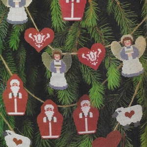 Könnte beinhalten: Eine Girlande mit Weihnachtsornamenten, die Engel, Weihnachtsmänner, Schafe und Herzen zeigen. Die Ornamente sind aus Filz und mit weißen und roten Stickereien verziert.