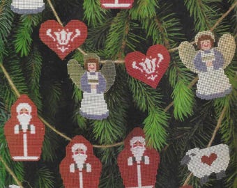 Könnte beinhalten: Eine Girlande mit Weihnachtsornamenten, die Engel, Weihnachtsmänner, Schafe und Herzen zeigen. Die Ornamente sind aus Filz und mit weißen und roten Stickereien verziert.
