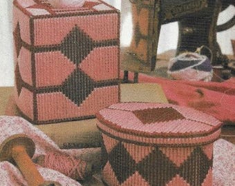 May include: Two pink and brown plastic canvas tissue box covers with a diamond pattern. The tissue box covers are sitting on a brown surface.