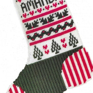 May include: A white Christmas stocking with a green and red striped pattern. The stocking has a red ribbon and a white lace trim at the top. The name "Amanda" is embroidered on the stocking in black.