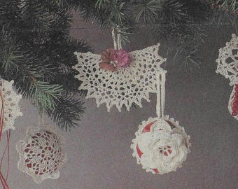 May include: Five crocheted Christmas ornaments hanging from a pine tree branch. The ornaments are white and feature different designs, including a snowflake, a flower, and a star.