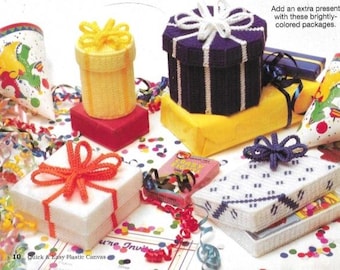 May include: A collection of colorful plastic canvas gift boxes with various designs, including a purple and white striped box, a yellow and white striped box, and a white box with a red bow. The boxes are surrounded by confetti and ribbons.