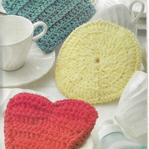 May include: Three crocheted dishcloths in different shapes and colors: a square teal dishcloth, a round yellow dishcloth, and a heart-shaped red dishcloth.