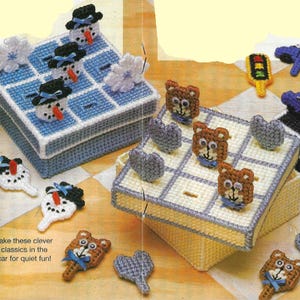 May include: Four colorful plastic canvas boxes with lids, each containing a different game. The games include tic-tac-toe with snowman pieces, tic-tac-toe with bear pieces, a car game with traffic light pieces, and a tic-tac-toe game with heart pieces. The text on the bottom of the image reads "Take these clever classics in the car for quiet fun!"