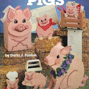 Pode incluir: Uma coleção de artesanato de porcos em tela de plástico rosa, incluindo uma capa para caixa de lenços, um leitão com uma bandana vermelha e um porco em um curral. A capa do livro de padrões diz "PLASTIC CANVAS PIGS" de Darla J. Fanton.