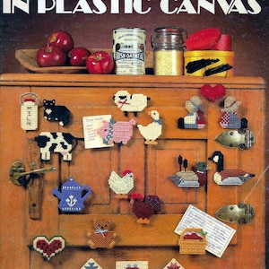 Puede incluir: Una colección de 20 imanes con temática campestre sobre una superficie de madera. Los imanes incluyen animales de granja, corazones y patrones geométricos. El texto "Magnets Go Country in Plastic Canvas" es visible.