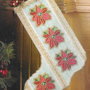May include: A white Christmas stocking with a gold trim and three red poinsettia flowers with green leaves. The stocking is decorated with gold beads and sequins.