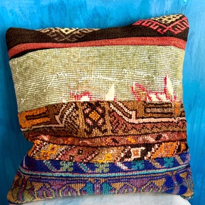 May include: A colorful throw pillow with a patchwork design featuring brown, green, blue, and orange hues. The pillow is made from a variety of fabrics and has a unique, hand-crafted look.