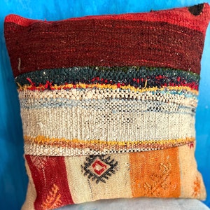 May include: A colorful, striped throw pillow with a geometric pattern in the center. The pillow is made of woven fabric and has a rustic, vintage look.
