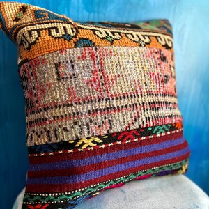 May include: A colorful patchwork pillow with a geometric pattern. The pillow is made from different fabrics and has a fringe border.