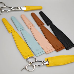 Puede incluir: Un juego de nueve fundas de cuero en varios colores, incluyendo amarillo, azul, rosa, marrón y negro. Las fundas están diseñadas para guardar tijeras.