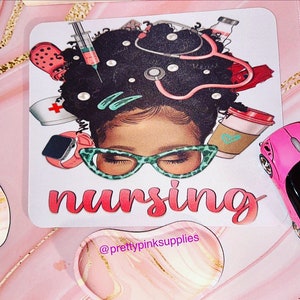 May include: A white mouse pad with a colorful illustration of a Black woman with an afro wearing glasses and surrounded by medical supplies. The text "nursing" is written in pink letters below the illustration. The text "@prettypinksupplies" is written in purple letters at the bottom of the mouse pad.